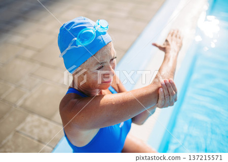 Older female swimmer stretching before swim in pool. Older female swimmer stretching before swim in pool. 137215571