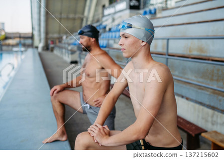 Father and teenage son preparing for swim training, stretching. Father and teenage son preparing for swim training, stretching. 137215602