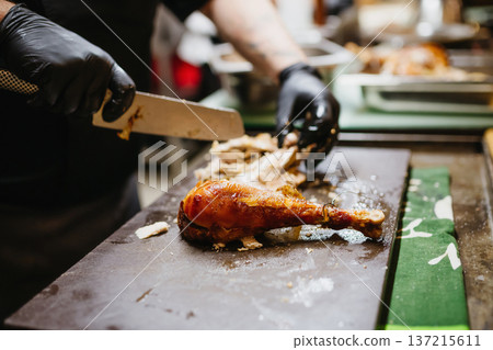 Cook portioning rotisserie chicken in kitchen. 137215611