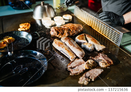 Grilled meat and vegetables on teppanyaki grill in restaurant kitchen. Grilled meat and vegetables on teppanyaki grill in restaurant kitchen. 137215636