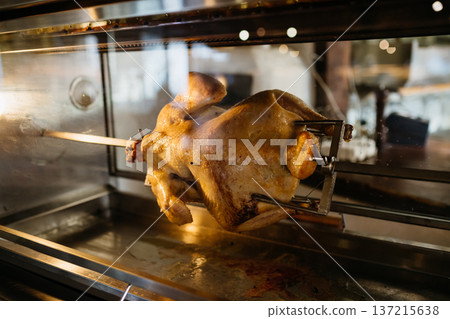 Rotisserie chicken cooking inside oven, roasted poultry preparation. Rotisserie chicken cooking inside oven, roasted poultry preparation. 137215638