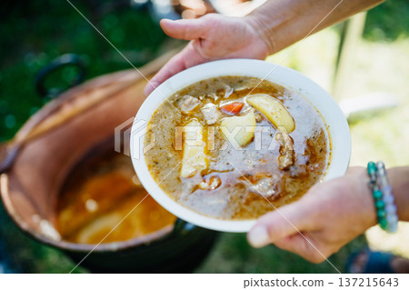 Traditional outdoor goulash served from kettle at family garden celebration 137215643