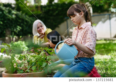 Portrait of cute schoolgirl taking care of plants in school garden during at outdoor sustainable education class. Concept of experiential learning and ecoliteracy. 137215681