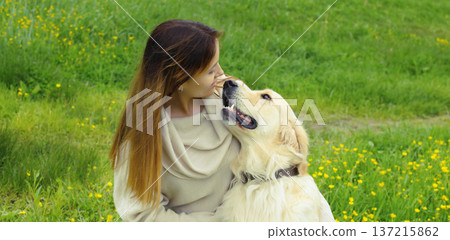 Happy owner young woman with Golden Retriever dog sitting on grass together in summer park Happy owner young woman with Golden Retriever dog sitting on grass together in summer park 137215862