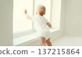 Little baby looking out the window in white room at home 137215864