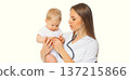 Young woman doctor holding baby and listens to his heart standing on white background 137215866