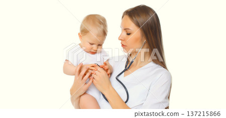 Young woman doctor holding baby and listens to his heart standing on white background Young woman doctor holding baby and listens to his heart standing on white background 137215866