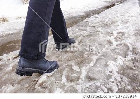 Spring slush. A man walks along a snowy road, the snow melts 137215914