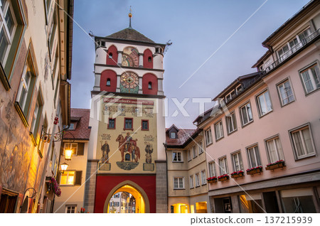 Wangen, germany, august 17, 2023. Martinstor tower with its historic frescoes and clock standing proudly amidst medieval buildings at twilight in wangen, germany 137215939