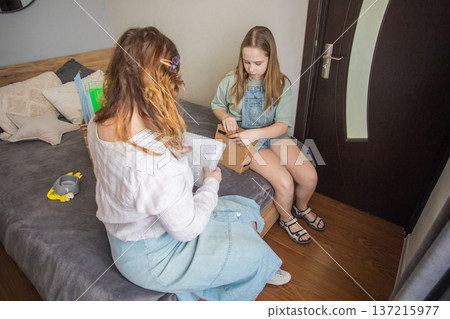 Two people sort pet supplies on a bed in a room with natural light during the day Two people sort pet supplies on a bed in a room with natural light during the day 137215977