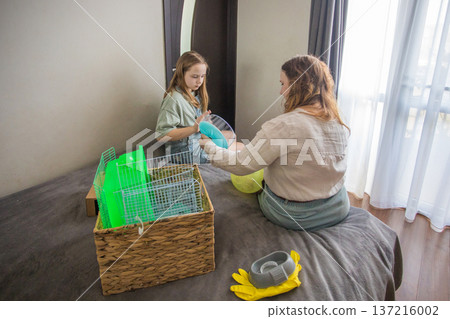 In a room with natural light, two girls work on putting together a pet. One girl holds a green ball  137216002
