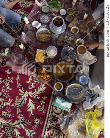 Realistic top view photograph of a traditional Arab family gathering around the table while preparing and sharing iftar during Ramadan. Authentic Ramadan atmosphere, traditional dishes, cultural Realistic top view photograph of a traditional Arab family gathering around the table while preparing and sharing iftar during Ramadan. Authentic Ramadan atmosphere, traditional dishes, cultural 137216128