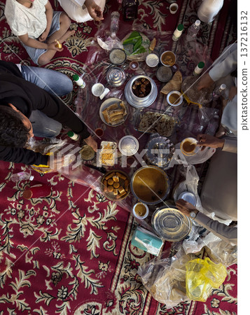 Realistic top view photograph of a traditional Arab family gathering around the table while preparing and sharing iftar during Ramadan. Authentic Ramadan atmosphere, traditional dishes, cultural Realistic top view photograph of a traditional Arab family gathering around the table while preparing and sharing iftar during Ramadan. Authentic Ramadan atmosphere, traditional dishes, cultural 137216132