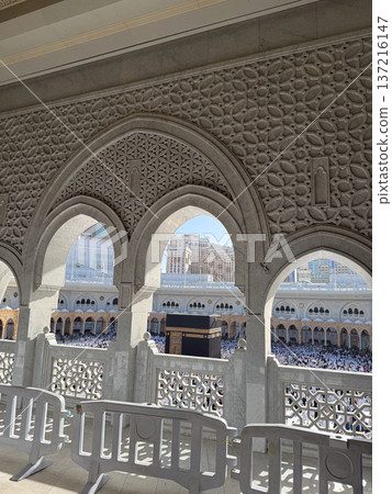 View of the Kaaba and pilgrims at Masjid al-Haram in Mecca through ornate stone arches 137216147