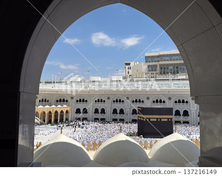 Pilgrims gathered around the Kaaba at Masjid al-Haram in Mecca framed by an arch Pilgrims gathered around the Kaaba at Masjid al-Haram in Mecca framed by an arch 137216149