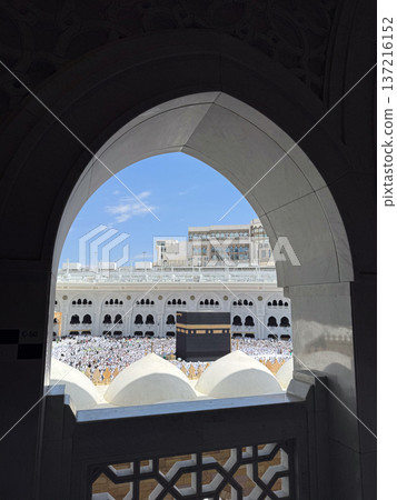 View of the Kaaba and pilgrims in Masjid al-Haram framed by an arched window in Mecca 137216152