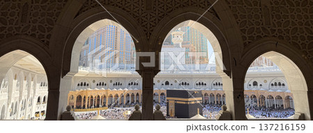 Pilgrims performing tawaf around the Kaaba seen through ornate mosque arches at Masjid al-Haram in Mecca 137216159