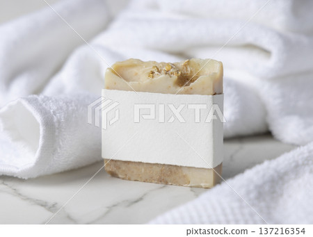 Mockup of beige solid soap bar with blank paper label near white bath towel, personal care packaging Mockup of beige solid soap bar with blank paper label near white bath towel, personal care packaging 137216354