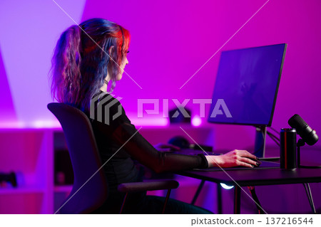 Young female gamer immersed in a vibrant gaming environment Young female gamer immersed in a vibrant gaming environment 137216544