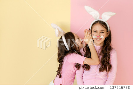 A child in an Easter bunny costume whispers an announcement about the eve of the holiday in his sister's ear A child in an Easter bunny costume whispers an announcement about the eve of the holiday in his sister's ear 137216788