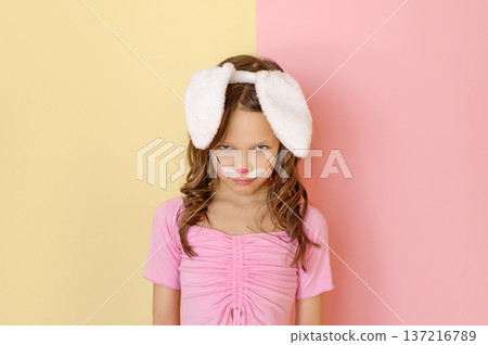 An angry, disgruntled Child in an Easter bunny costume glares maliciously from under his forehead 137216789
