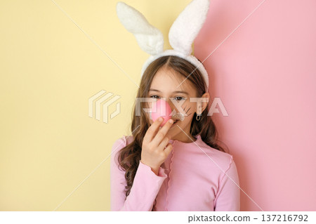 Funny humorous beautiful girl with makeup in a bunny costume puts an Easter egg to her nose like a clown 137216792