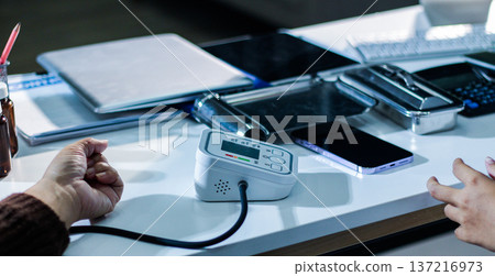 A doctor's hands carefully taking a patient's blood pressure using a sphygmomanometer. A doctor's hands carefully taking a patient's blood pressure using a sphygmomanometer. 137216973