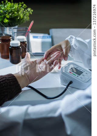 A doctor's hands carefully taking a patient's blood pressure using a sphygmomanometer. A doctor's hands carefully taking a patient's blood pressure using a sphygmomanometer. 137216974
