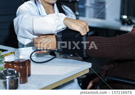 A doctor's hands carefully taking a patient's blood pressure using a sphygmomanometer. A doctor's hands carefully taking a patient's blood pressure using a sphygmomanometer. 137216978