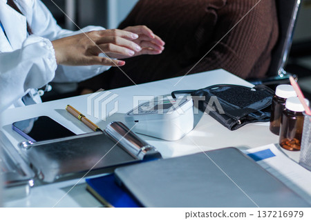 A doctor's hands carefully taking a patient's blood pressure using a sphygmomanometer. 137216979