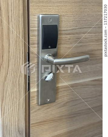 Closeup of modern wooden door with metal handle, showcasing sleek design and functionality Closeup of modern wooden door with metal handle, showcasing sleek design and functionality 137217030