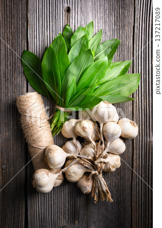 Bundle of wild garlic with garlic bulbs on wooden surface Bundle of wild garlic with garlic bulbs on wooden surface 137217089
