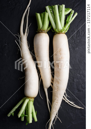 Fresh daikon radish arranged vertically on black background Fresh daikon radish arranged vertically on black background 137217114