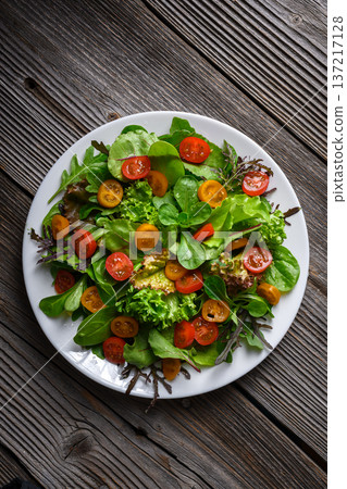 Mixed salad greens with cherry tomatoes arranged symmetrically on white plate Mixed salad greens with cherry tomatoes arranged symmetrically on white plate 137217128