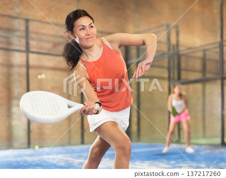 Focused woman playing paddle ball on closed court 137217260
