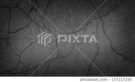 Textured black concrete surface with visible cracks and scratches, showcasing a rough and weathered appearance suitable for backgrounds or design elements 137217295