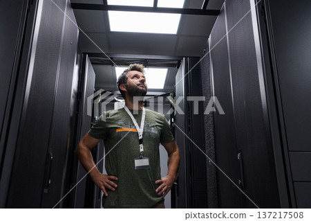 Confident IT technician inspecting server racks in a modern data center with hands on hips Confident IT technician inspecting server racks in a modern data center with hands on hips 137217508
