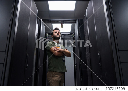 IT technician inspecting servers in a modern data center aisle with focused expression IT technician inspecting servers in a modern data center aisle with focused expression 137217509