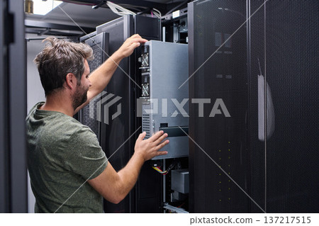 Server technician installing a rack server in a modern data center performing IT maintenance and hardware upgrade Server technician installing a rack server in a modern data center performing IT maintenance and hardware upgrade 137217515