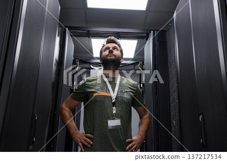 Data center technician inspecting server racks in a modern data center with confident professional stance Data center technician inspecting server racks in a modern data center with confident professional stance 137217534