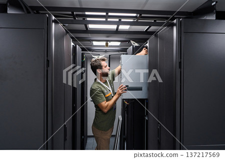 IT technician installing server hardware in a data center server rack maintenance environment 137217569