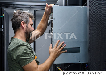 Technician installing server hardware in a data center rack performing IT maintenance and equipment upgrade Technician installing server hardware in a data center rack performing IT maintenance and equipment upgrade 137217578