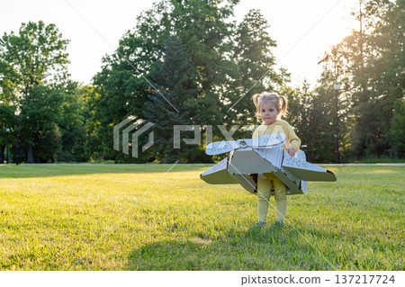 Airplane costume. Toddler imagination flying. Girl outdoor yellow grass fun. 137217724