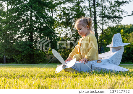 Little pilot. Airplane cardboard child costume. Fantasy game yellow grass. 137217732