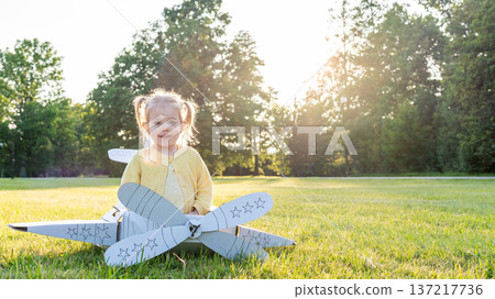 Little pilot. Airplane cardboard child costume. Fantasy game yellow grass. Little pilot. Airplane cardboard child costume. Fantasy game yellow grass. 137217736