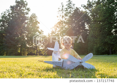 Airplane child. Girl flying cardboard pilot. Outdoor yellow costume grass park. Airplane child. Girl flying cardboard pilot. Outdoor yellow costume grass park. 137217748