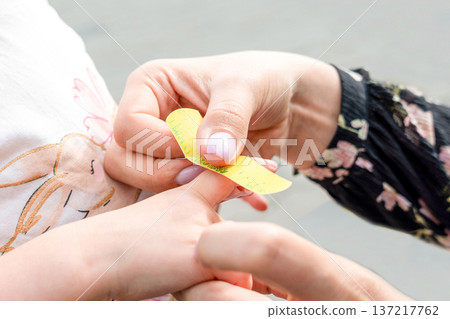 Child medical care. Toddler receiving adhesive treatment outside. Caring parent concept. Child medical care. Toddler receiving adhesive treatment outside. Caring parent concept. 137217762