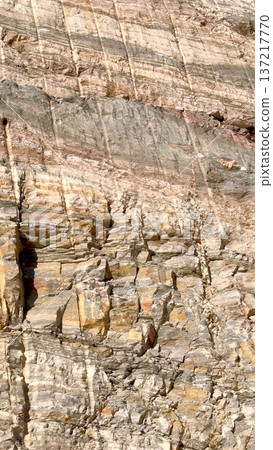 Impressive Stone Structure Featuring Intricate Sediment Layers And Shaded Grooves. Majestic Cliff Face Displaying Complex Stratified Patterns Along With Profound Shadowed Crevices Impressive Stone Structure Featuring Intricate Sediment Layers And Shaded Grooves. Majestic Cliff Face Displaying Complex Stratified Patterns Along With Profound Shadowed Crevices 137217770
