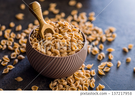 Wholegrain conchiglie pasta in bowl on black table. 137217958
