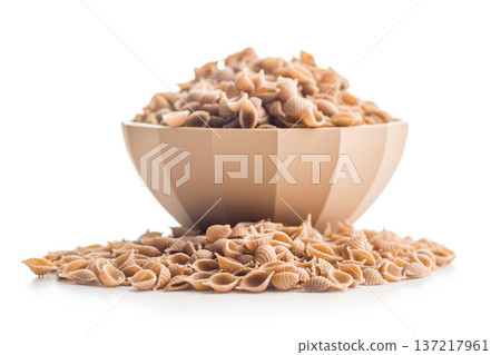 Wholegrain conchiglie pasta in bowl isolated on white background. Wholegrain conchiglie pasta in bowl isolated on white background. 137217961